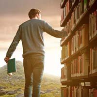homme debout avec livre à la main devant une bibliothèquqe