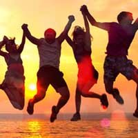 groupe de jeunes gens heureux sautant à la plage lors d'un beau coucher de soleil d'été